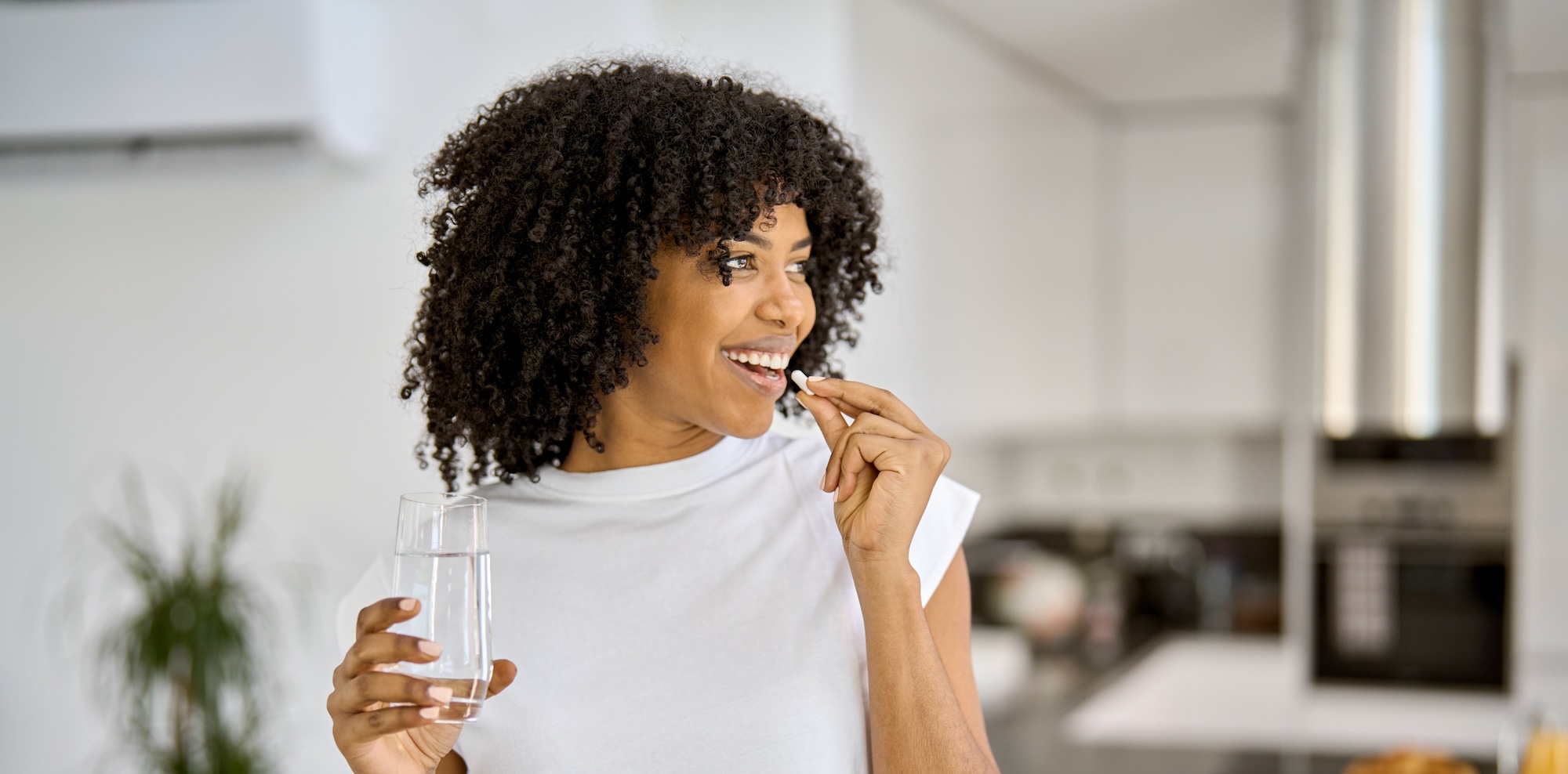 Woman in kitchen taking supplement