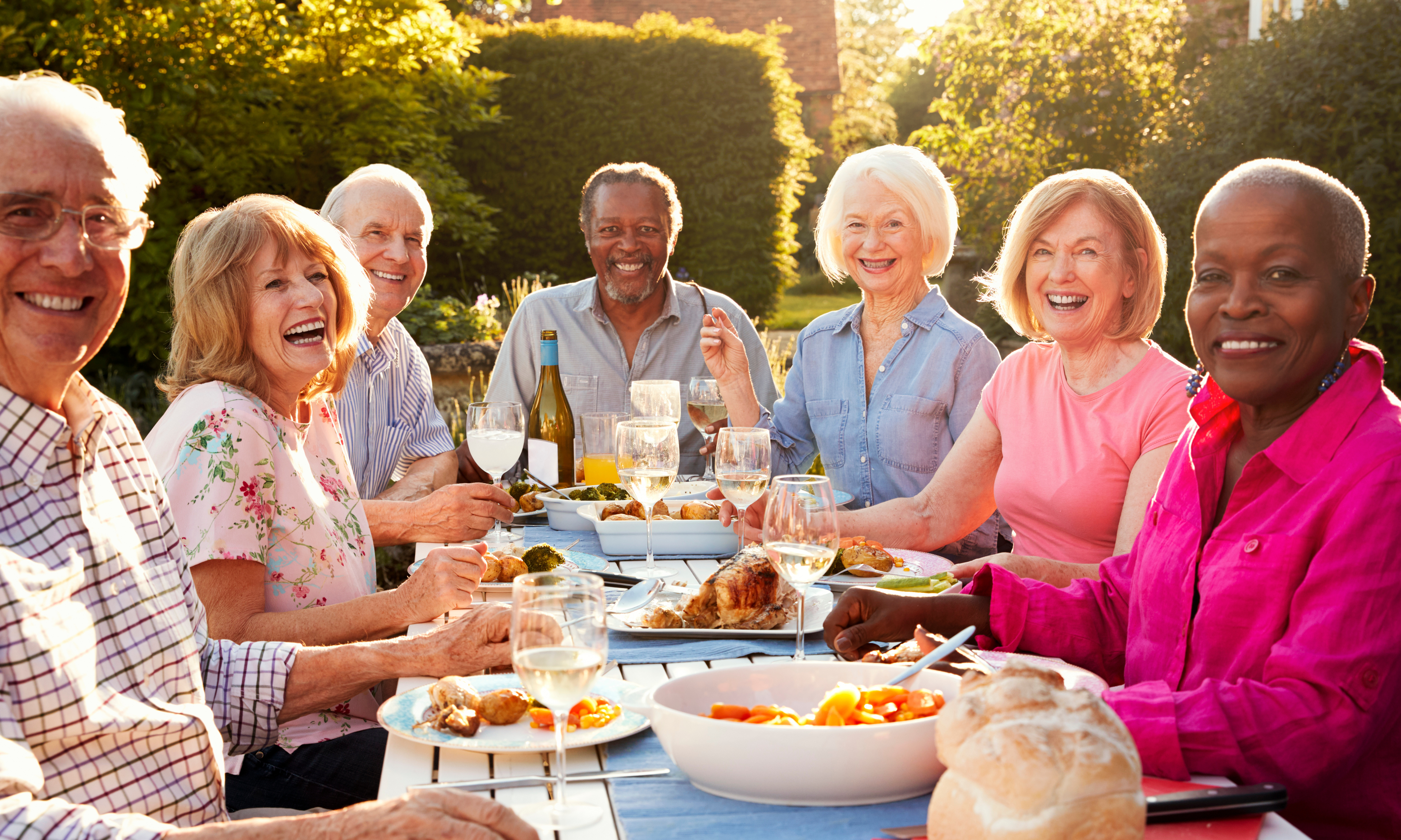 Seniors smiling and laughing at table with food outside