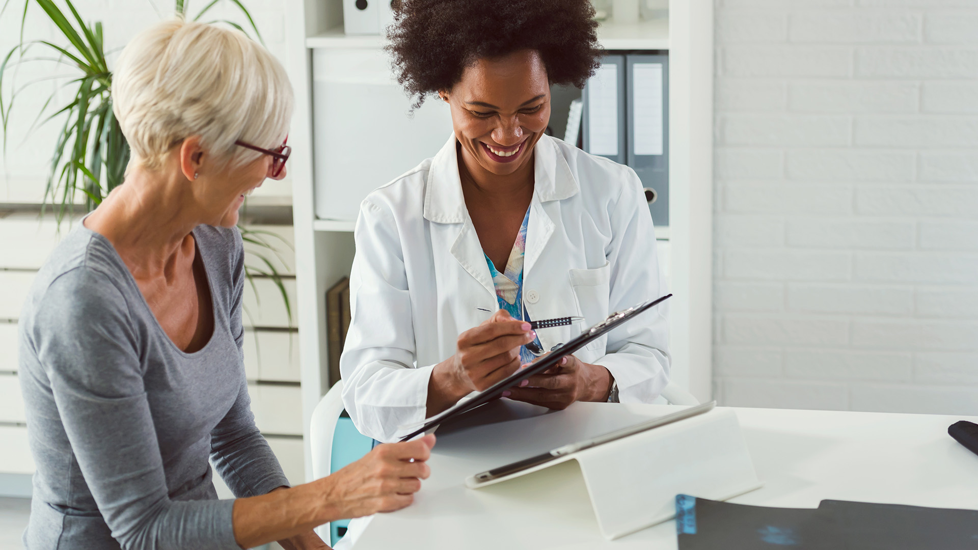 Senior woman looking at medical charts with woman doctor