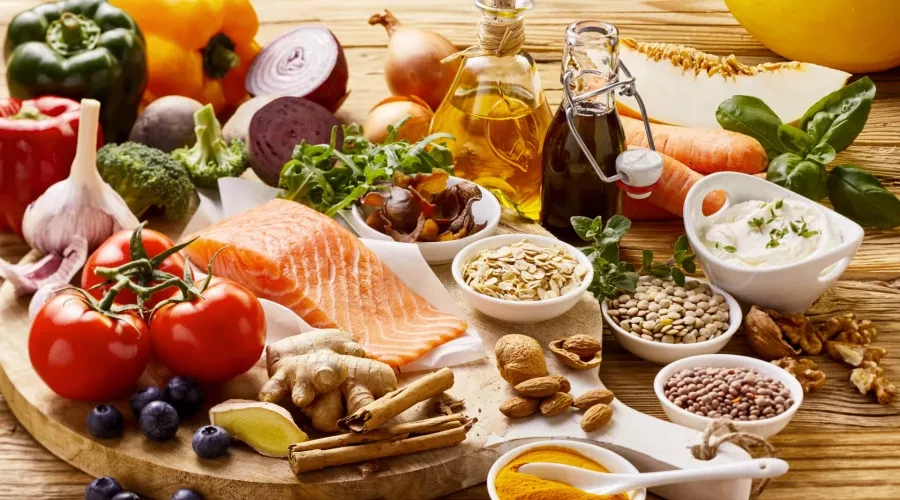 Wood trable with colorful food, salmon, vegetables, yogurt and various nuts