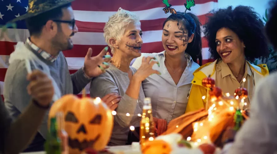 4 friends dressed up for Halloween and laughing around a table with Halloween decorations