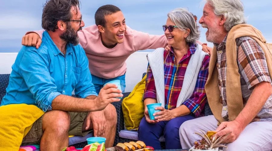 4 people enjoying snack and drinks on patio laughing
