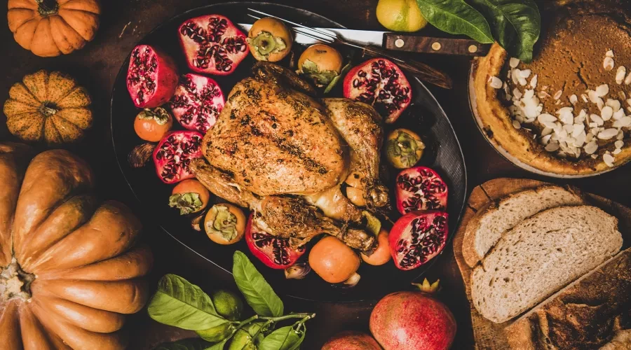 Table with colorful food displayed, roasted chicken with pomegranate, pie, baked bread