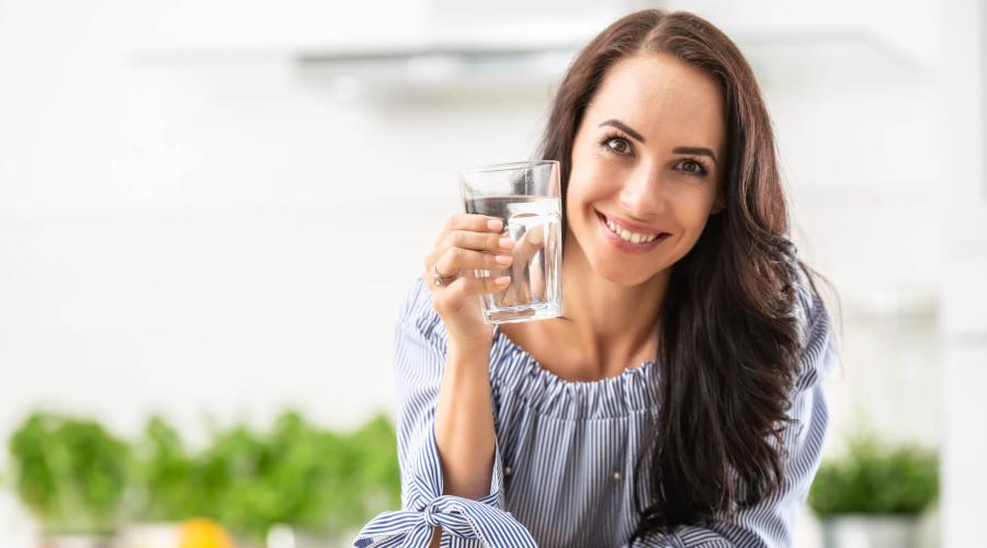 Middle aged woman smiling and holding a glass of water