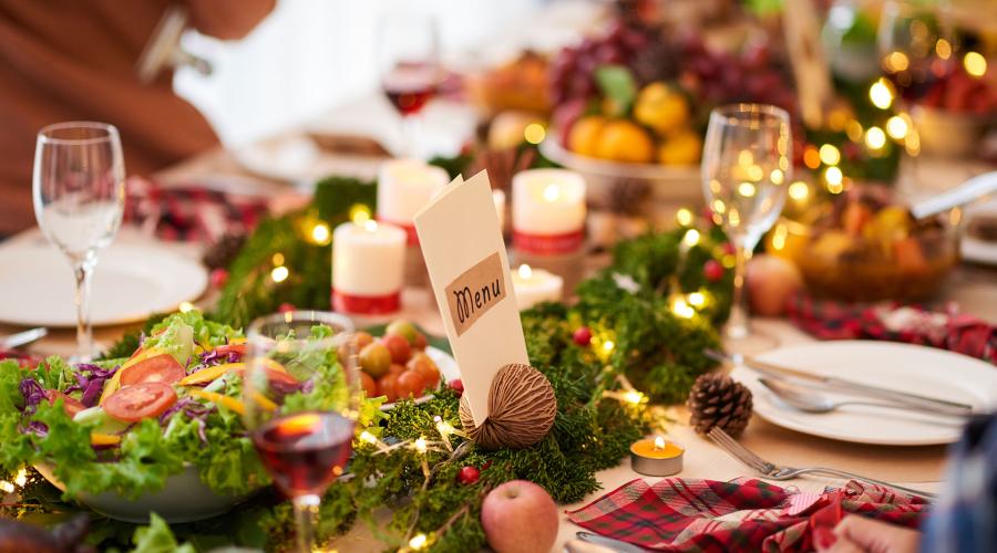 Holiday table settings, candles, wineglasses, salad, pinecones, holiday folded napkins, menu card