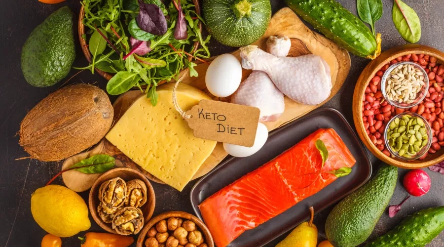 Wood table with raw chickem, eggs, cheese, fresh salmon, assorted nuts and vegetables
