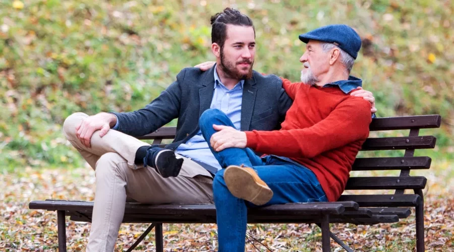 Young man taking to his father in park on park bench
