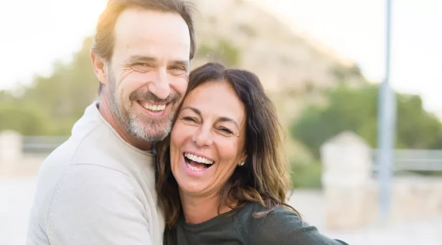 Middle-aged couple embracing and laughing outdoors