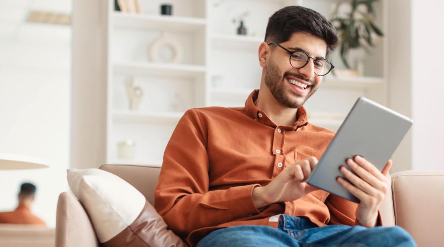 Man on couch, smiling and looking at iPad