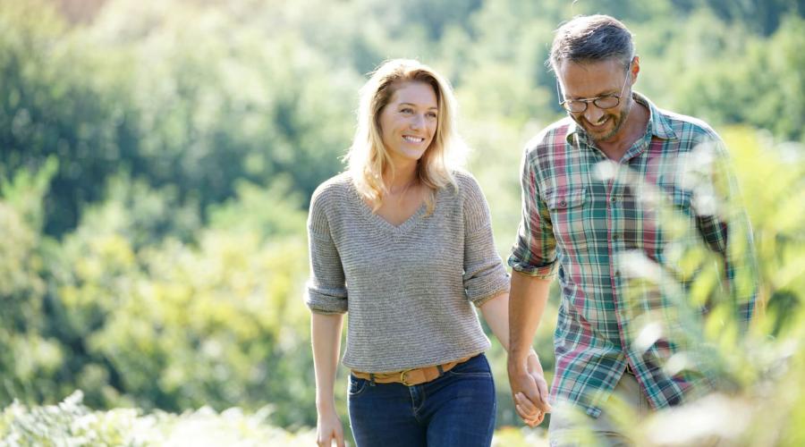 Middle-aged couple smiling and walking outside in nature