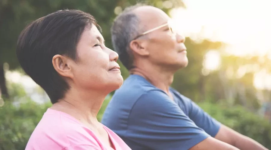 Couple with eyes closed, outside in the sun breathing