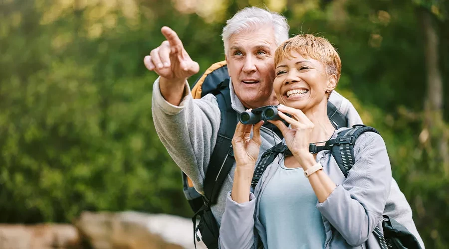Older couple outdoors, man pointing and woman with binoculars