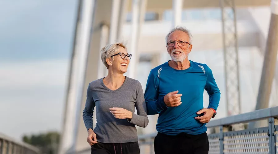 Man and woman smiling and running on a bridge