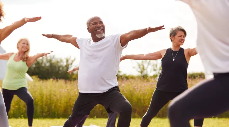 Middle aged man, outside doing yoga with a class