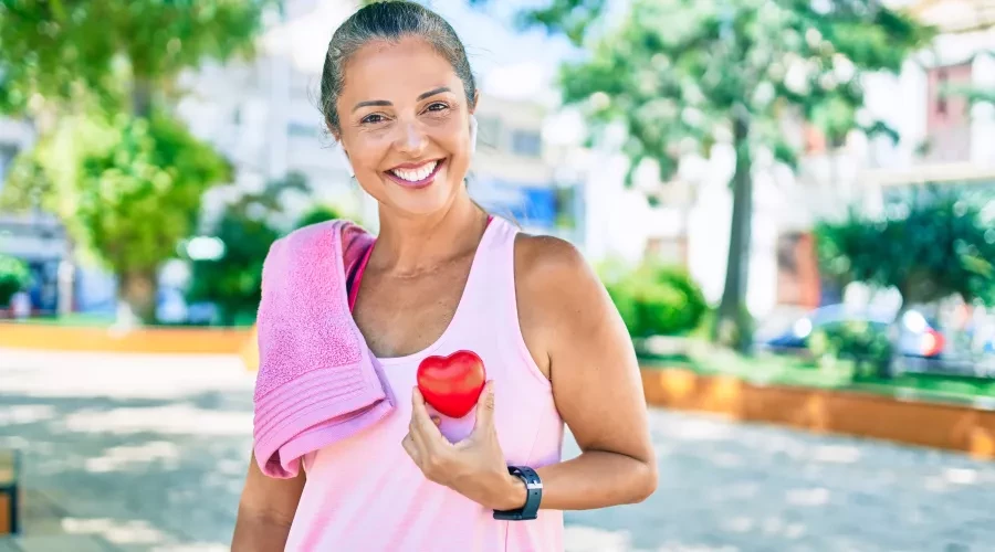 Woman outside, after workout holding small heart object