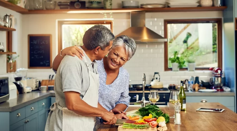 Couple in kitchen smiling and preparing food
