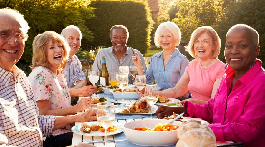 Seniors smiling and laughing at table with food outside