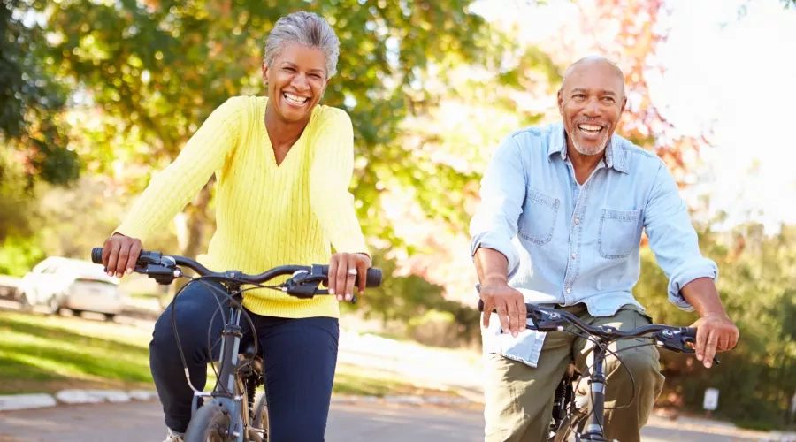 Couple outside, riding bikes on path and smiling