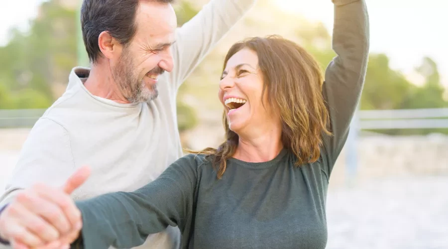 Couple in their 40's dancing and laughing in the sun