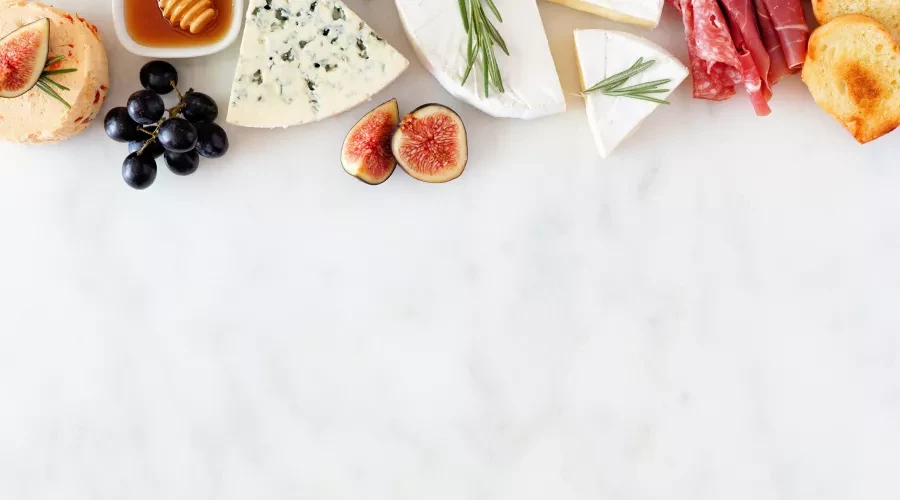 Typical French ingredients (cheeses, meats, a dish of honey, grapes, figs, and bread) arranged decoratively.