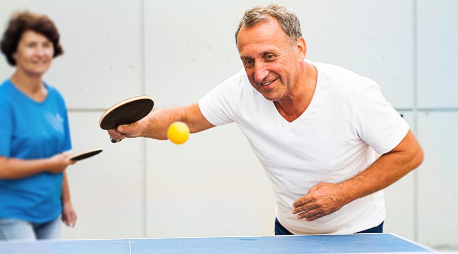An older man and woman playing ping pong.