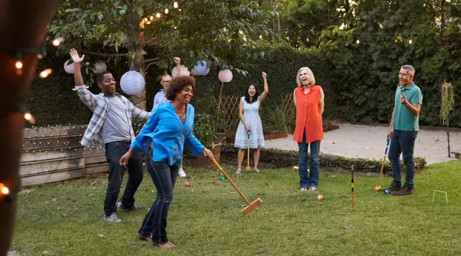 Couples laughing in backyard playing Croquet on lawn