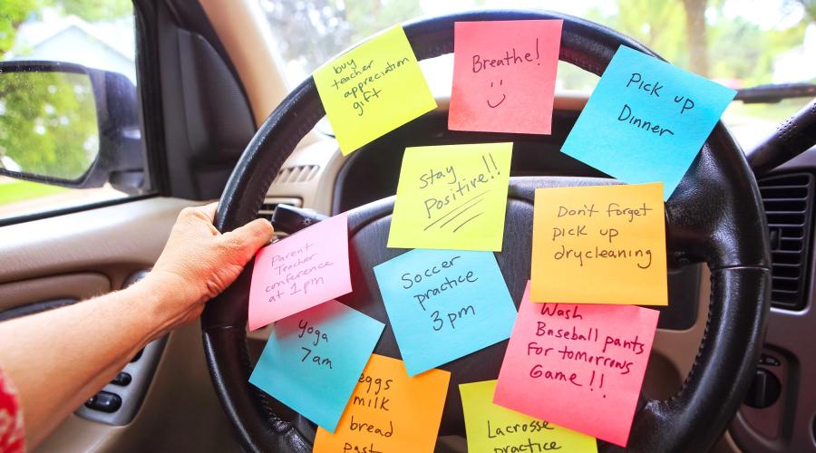 Person in car with stickie note reminders stuck to the steering wheel