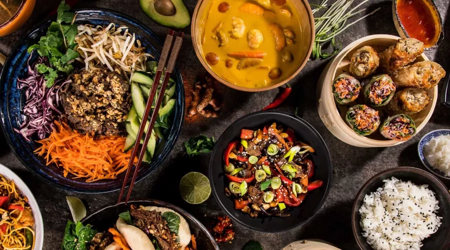 Table with bowls full of colorful of Thai Food and chops sticks