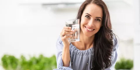 Middle aged woman smiling and holding a glass of water