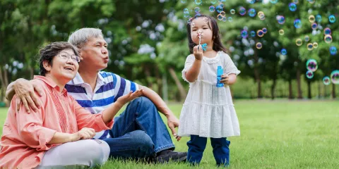 Senior couple in the park with grand daughter blowing bubbles