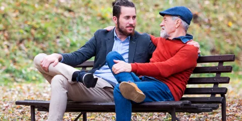 Young man taking to his father in park on park bench 