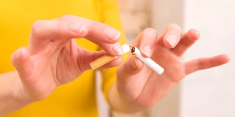 Person breaking cigarette in half with hands