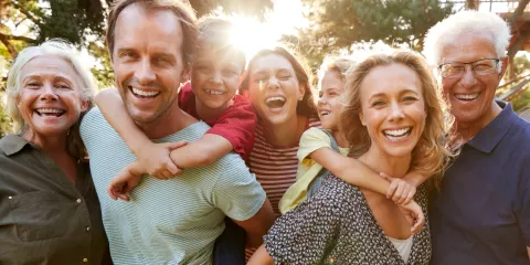 Middle-Aged Mother and Father with kids and grandparents laughing and smiling outside 