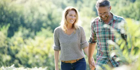 Middle-aged couple smiling and walking outside in nature