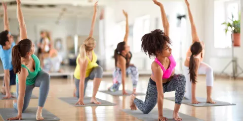 Women in colorful yoga gear, in yoga studio, yoga stretching pose together