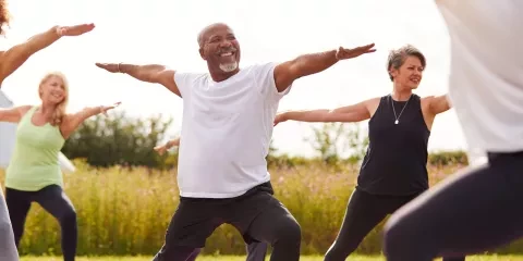 Middle aged man, outside doing yoga with a class