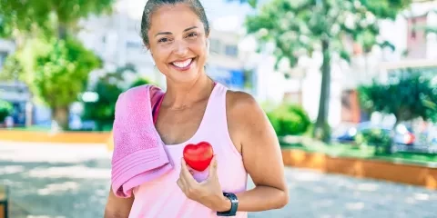 Woman outside, after workout holding small heart object
