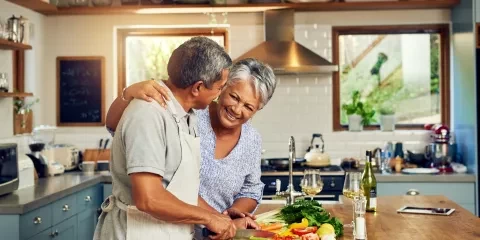 Couple in kitchen smiling and preparing food 