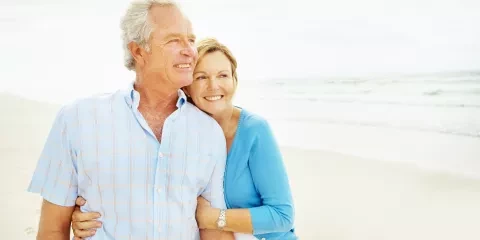 Couple on the beach, holding each other and smiling 