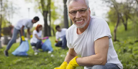 Middle aged man outside picking up trash volunteering 