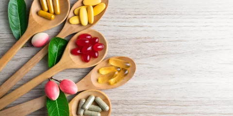 Supplement vitamins on wooden spoons on cooking board