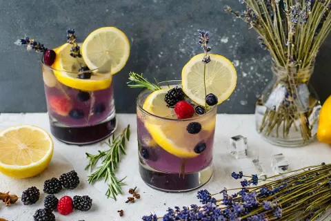 berry bliss mocktail on table with lemons, berries and lavender 