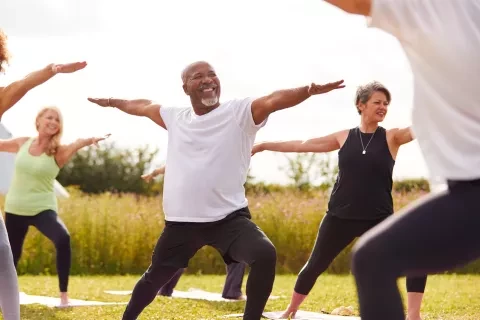 Middle aged man, outside doing yoga with a class