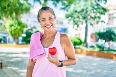 Woman outside, after workout holding small heart object