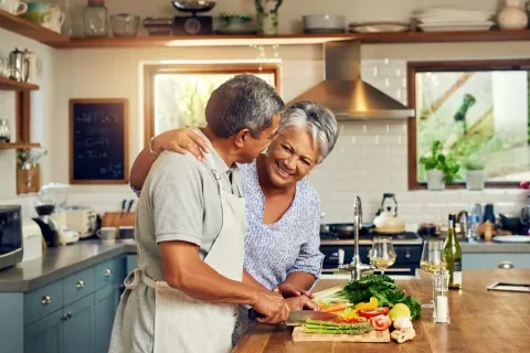 Couple in kitchen smiling and preparing food 