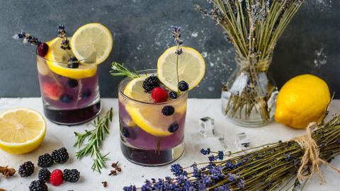 berry bliss mocktail on table with lavendar, blueberries and lemon